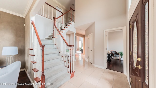 foyer entrance featuring baseboards, crown molding, a high ceiling, and light tile patterned flooring