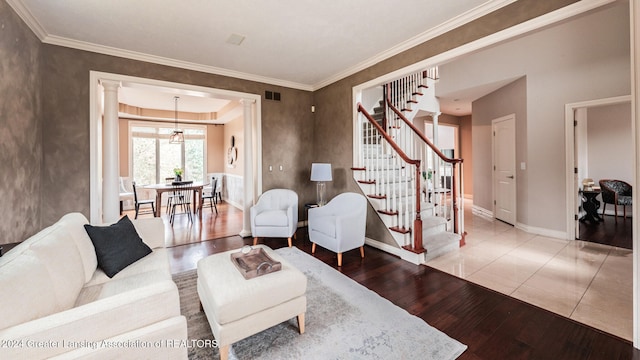 living area featuring visible vents, ornamental molding, wood finished floors, baseboards, and stairs