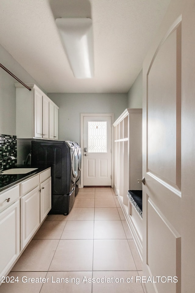 laundry room with light tile patterned floors, cabinet space, a sink, and separate washer and dryer