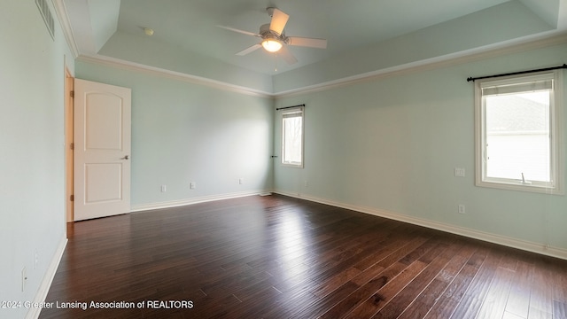 empty room featuring dark wood-style floors, a tray ceiling, ceiling fan, and baseboards