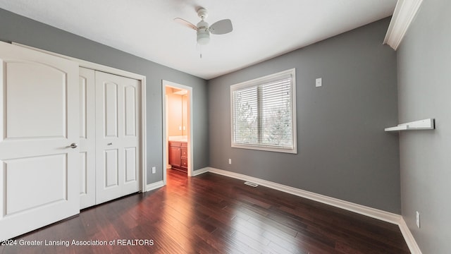 unfurnished bedroom with ceiling fan, a closet, baseboards, and dark wood-type flooring