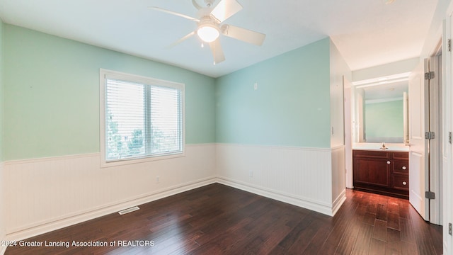 unfurnished bedroom featuring visible vents, a ceiling fan, wainscoting, dark wood-style flooring, and a sink