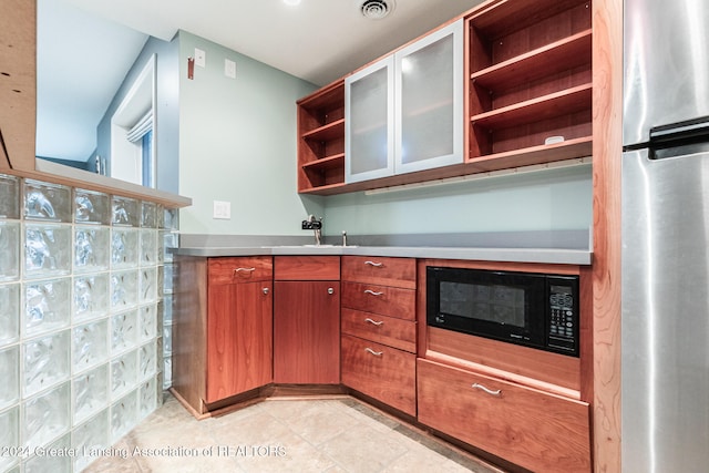 kitchen with black microwave, a sink, visible vents, freestanding refrigerator, and open shelves