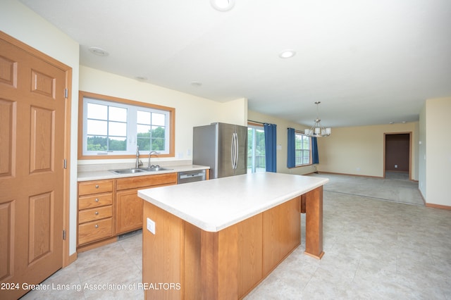 kitchen featuring appliances with stainless steel finishes, sink, a center island, hanging light fixtures, and a chandelier