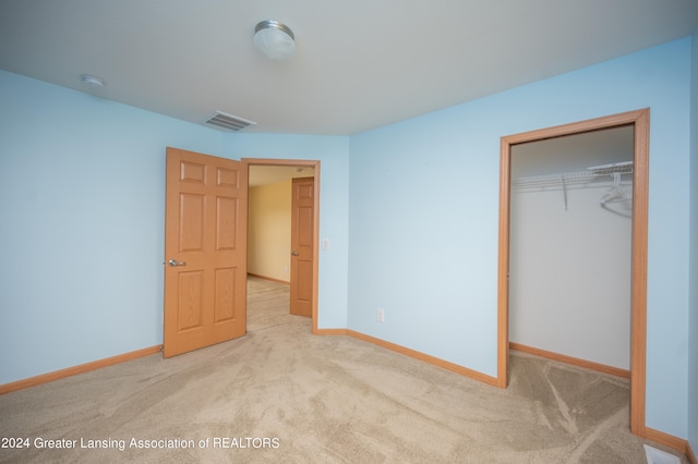 unfurnished bedroom featuring light carpet and a closet