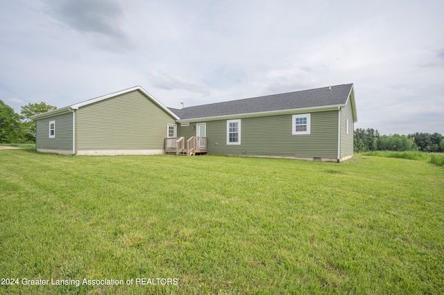 rear view of property featuring a deck and a lawn