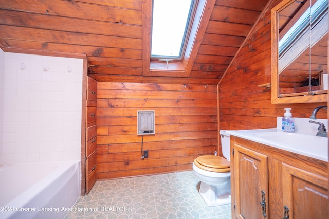 bathroom with a tub to relax in, wood walls, toilet, vaulted ceiling with skylight, and vanity