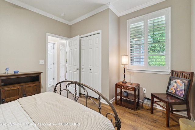 bedroom featuring light wood-type flooring, crown molding, and a closet