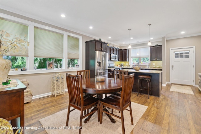 dining space with light hardwood / wood-style floors, a wealth of natural light, and crown molding