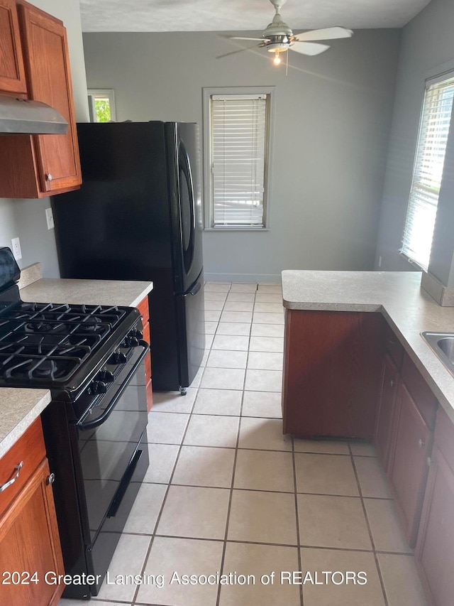 kitchen with range hood, black appliances, ceiling fan, and light tile patterned flooring