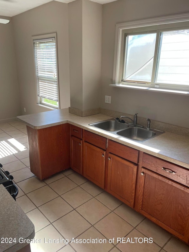 kitchen with kitchen peninsula, light tile patterned flooring, and sink