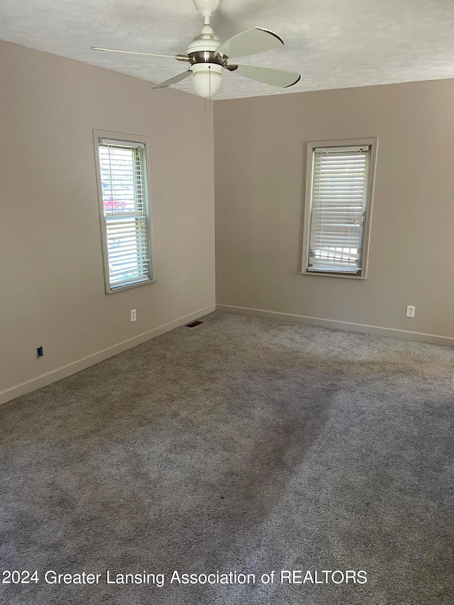 spare room featuring a textured ceiling, carpet, and ceiling fan