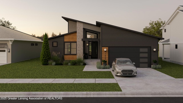 contemporary home featuring concrete driveway, a lawn, and an attached garage