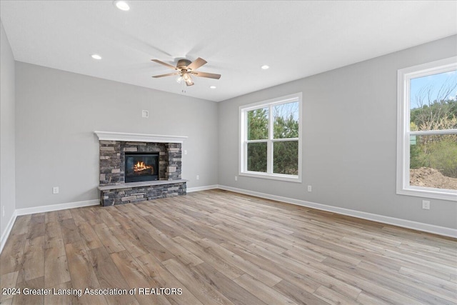 unfurnished living room featuring a stone fireplace, recessed lighting, wood finished floors, and baseboards