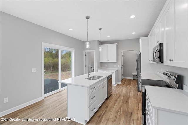 kitchen featuring a center island with sink, light wood-style flooring, appliances with stainless steel finishes, light countertops, and a sink