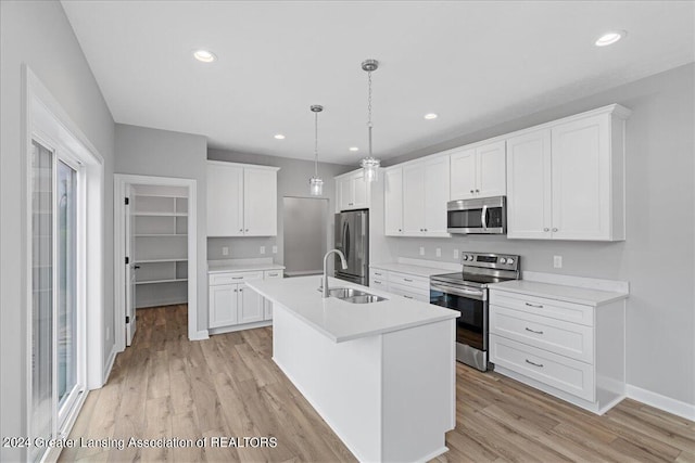 kitchen featuring light wood finished floors, appliances with stainless steel finishes, light countertops, white cabinetry, and a sink