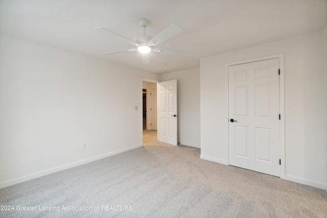 unfurnished bedroom with ceiling fan, light colored carpet, and a closet