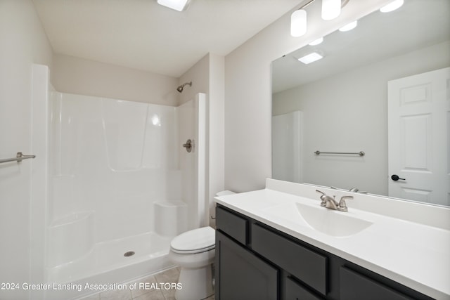 bathroom featuring tile patterned flooring, a shower, vanity, and toilet