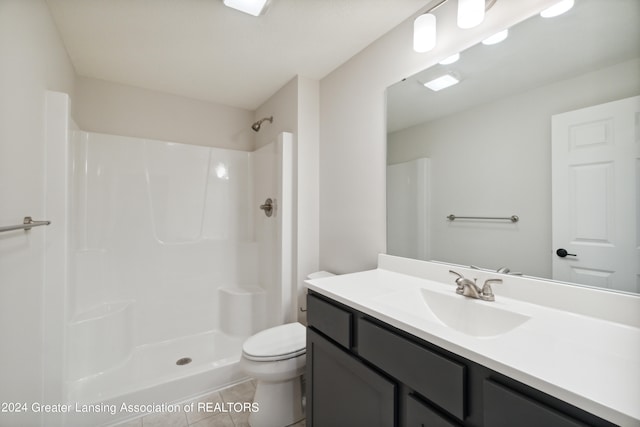 bathroom with tile floors, walk in shower, toilet, and vanity with extensive cabinet space