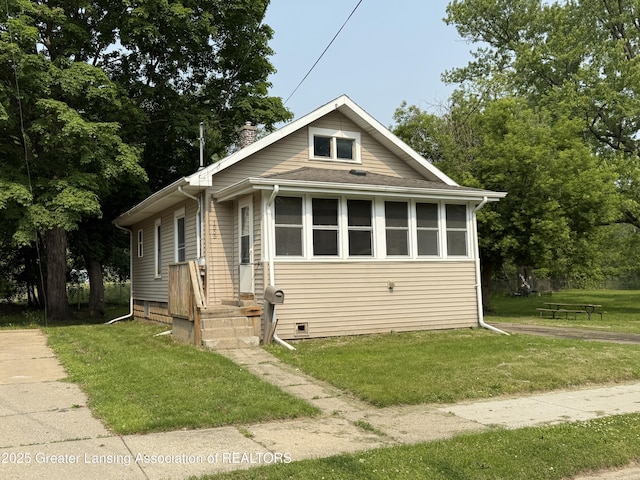 1555 Roosevelt Ave, Lansing, MI 48915 - bungalow featuring a front lawn, a chimney, and roof with shingles