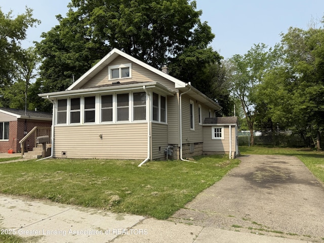 1555 Roosevelt Ave, Lansing, MI 48915 - bungalow-style house with a front lawn and driveway