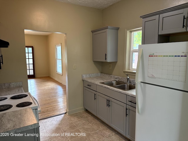 1555 Roosevelt Ave, Lansing, MI 48915 - kitchen with freestanding refrigerator, gray cabinetry, plenty of natural light, light countertops, and a textured ceiling