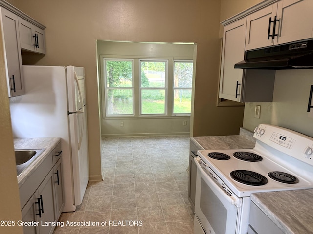 1555 Roosevelt Ave, Lansing, MI 48915 - kitchen with white appliances, under cabinet range hood, light countertops, and gray cabinetry