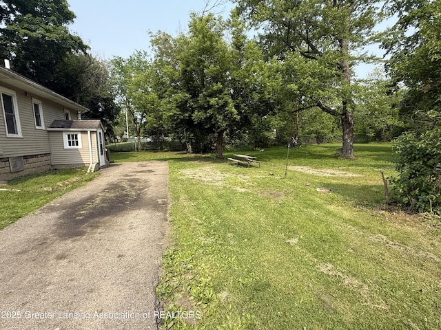 1555 Roosevelt Ave, Lansing, MI 48915 - view of green lawn with asphalt driveway and view of wooded area