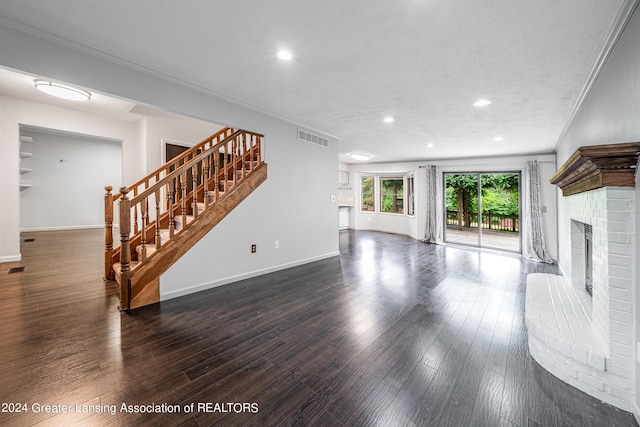 unfurnished living room featuring dark hardwood / wood-style flooring, a brick fireplace, and ornamental molding