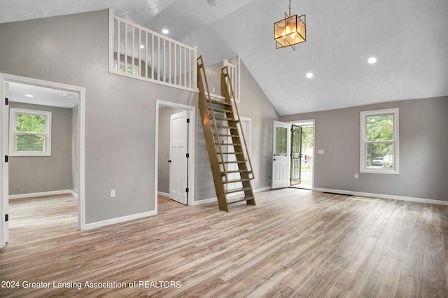 unfurnished living room with high vaulted ceiling, light hardwood / wood-style flooring, and a wealth of natural light