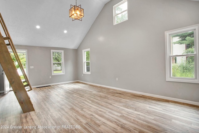 unfurnished living room with high vaulted ceiling, light wood-type flooring, and a wealth of natural light