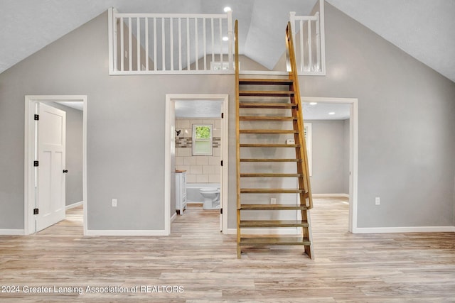 stairway featuring light wood-type flooring and a towering ceiling