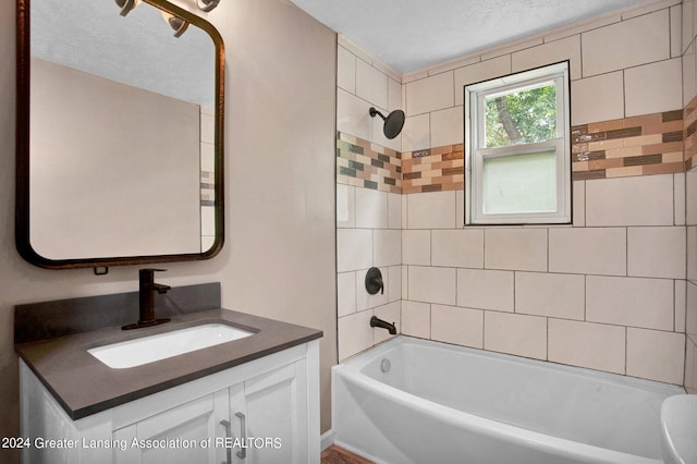 bathroom featuring a textured ceiling, vanity, and tiled shower / bath