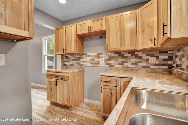 kitchen with decorative backsplash, light hardwood / wood-style flooring, light brown cabinetry, and a textured ceiling