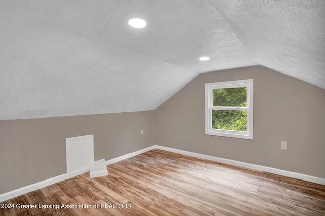 bonus room with a textured ceiling, lofted ceiling, and hardwood / wood-style floors