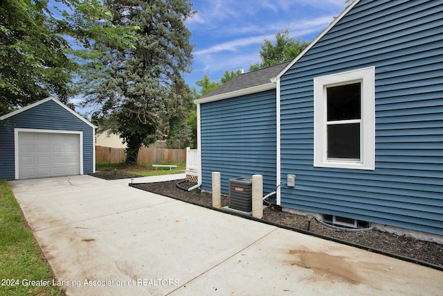 view of home's exterior featuring cooling unit, a garage, and an outbuilding