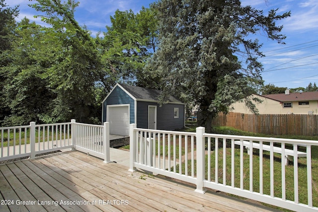 deck featuring a garage, a lawn, and an outdoor structure