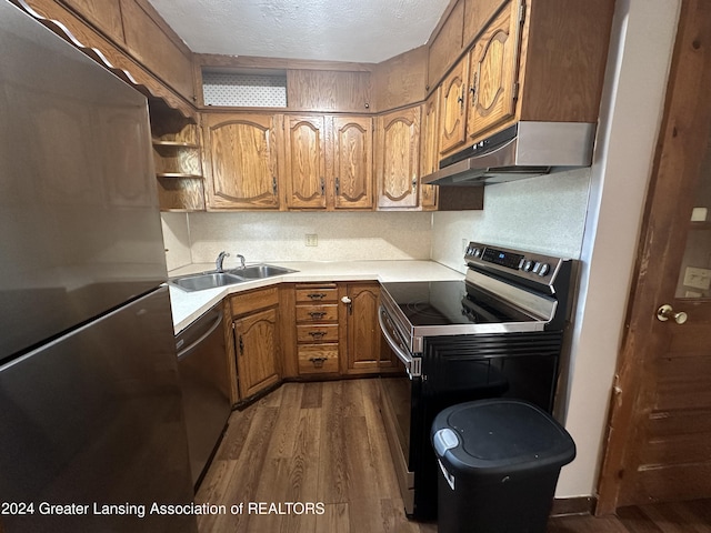 kitchen with sink, stainless steel appliances, dark hardwood / wood-style flooring, a textured ceiling, and decorative backsplash