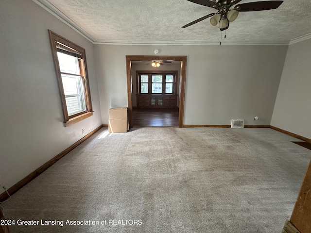 carpeted spare room with a textured ceiling, ceiling fan, and crown molding