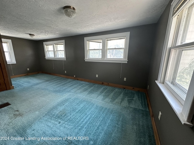 spare room featuring carpet flooring and a textured ceiling