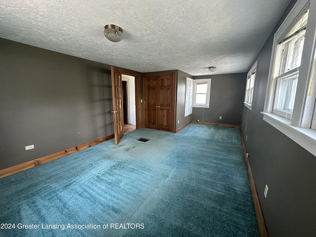 interior space featuring dark colored carpet and a textured ceiling