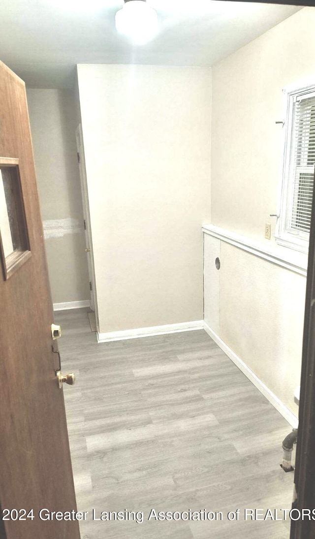 clothes washing area featuring wood finished floors and baseboards