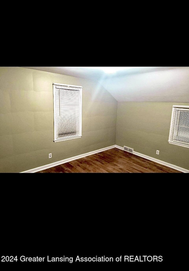 interior space with vaulted ceiling, visible vents, and wood finished floors