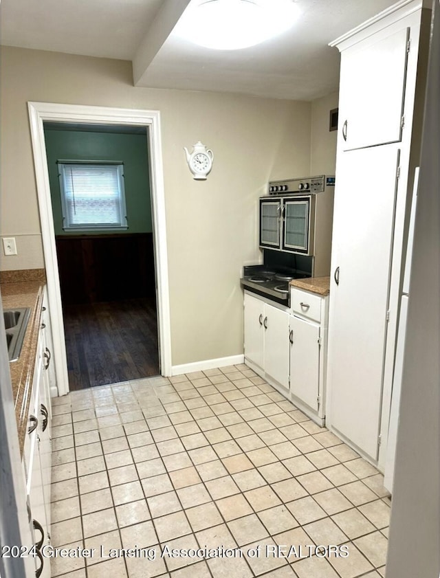 kitchen with white cabinetry, light tile patterned floors, baseboards, and a sink