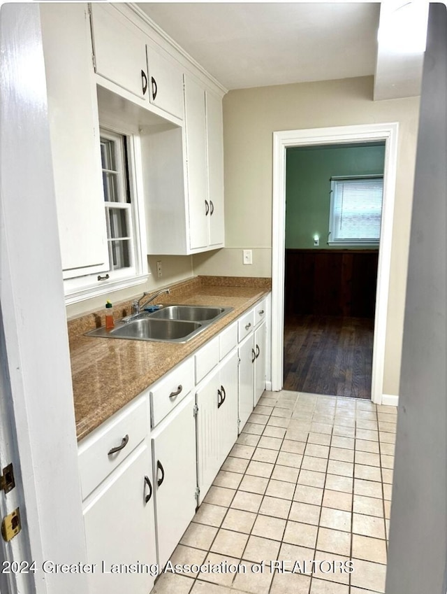 kitchen featuring white cabinets, light tile patterned flooring, and sink