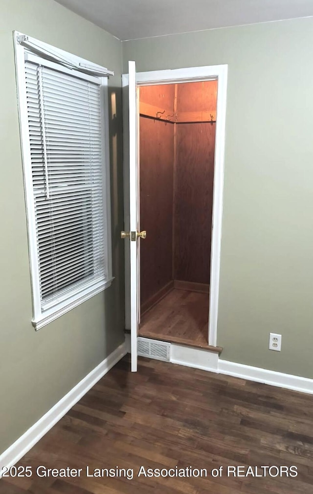 unfurnished bedroom with dark wood finished floors, visible vents, baseboards, and a closet