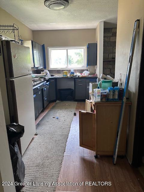 kitchen featuring white refrigerator, gray cabinetry, a textured ceiling, and light hardwood / wood-style flooring