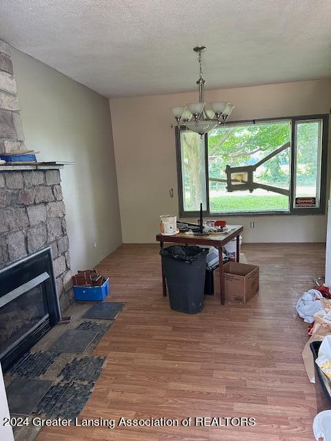 dining room with wood-type flooring, a stone fireplace, and a textured ceiling