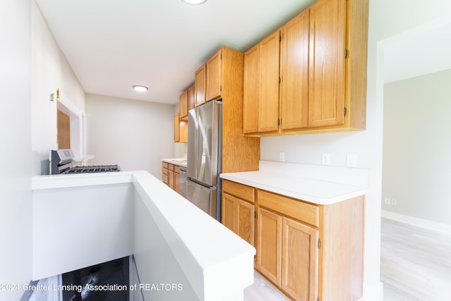 kitchen with stainless steel fridge, range, and light wood-type flooring