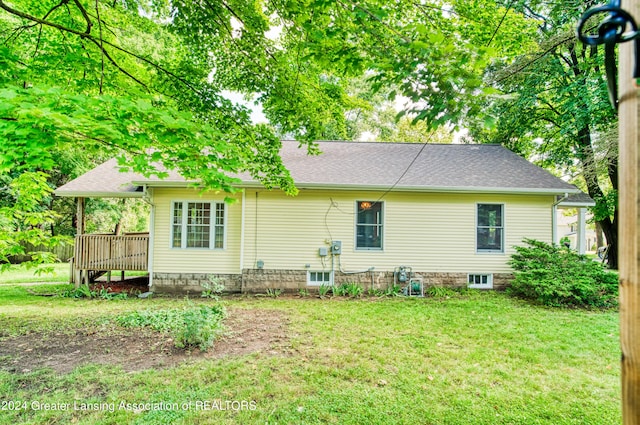 back of property with a wooden deck and a lawn